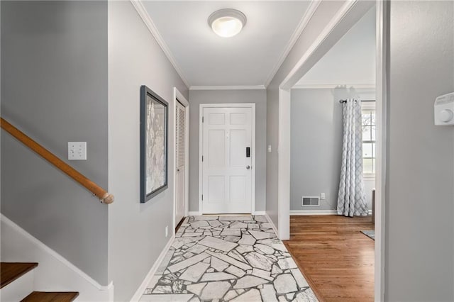 foyer entrance with baseboards, visible vents, light wood finished floors, stairs, and crown molding