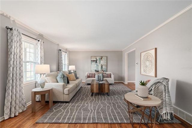 living area with visible vents, ornamental molding, baseboards, and wood finished floors