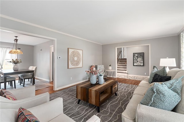 living area with baseboards, wood finished floors, stairs, and crown molding