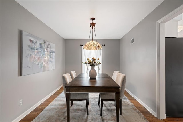 dining room featuring visible vents, baseboards, and wood finished floors