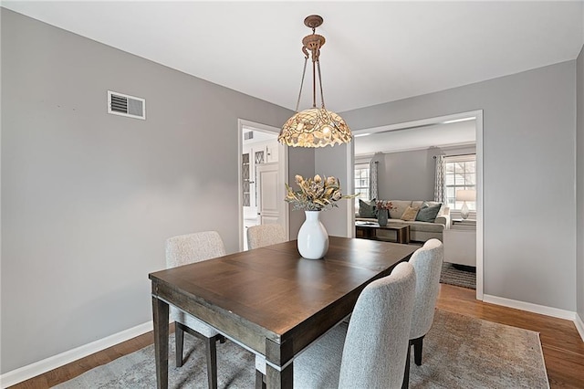 dining room featuring visible vents, baseboards, and wood finished floors