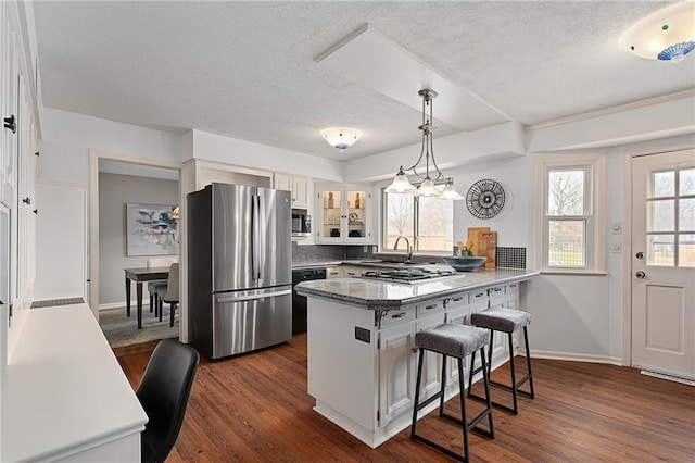 kitchen featuring a peninsula, a kitchen breakfast bar, a healthy amount of sunlight, and appliances with stainless steel finishes