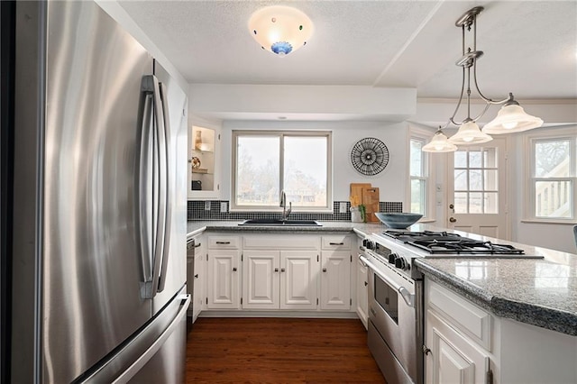 kitchen featuring light stone countertops, dark wood finished floors, stainless steel appliances, white cabinetry, and a sink