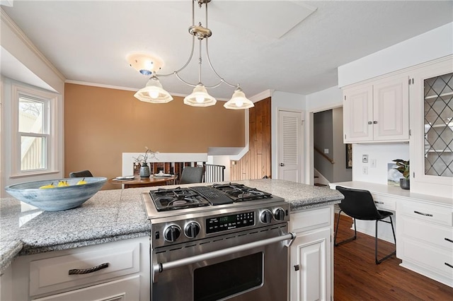 kitchen with gas stove, dark wood finished floors, ornamental molding, hanging light fixtures, and white cabinets