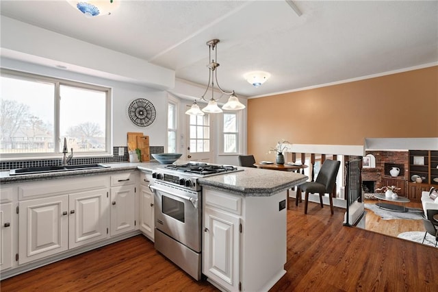 kitchen featuring high end stainless steel range, a sink, wood finished floors, white cabinetry, and a peninsula