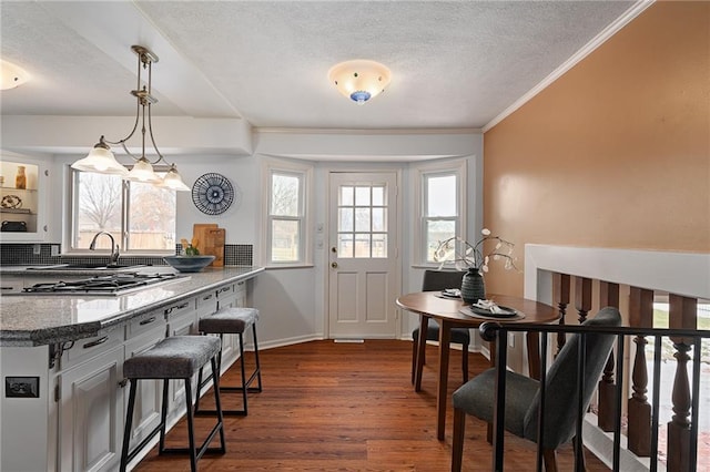 dining space featuring crown molding, dark wood-style floors, baseboards, and a textured ceiling