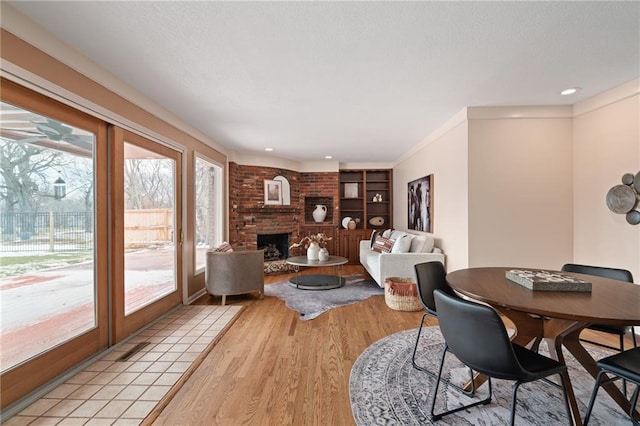 dining area with light wood finished floors, a fireplace, and a textured ceiling