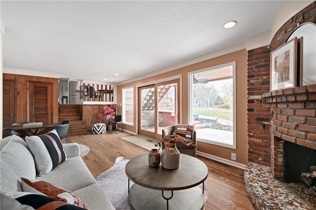 living area featuring visible vents, baseboards, recessed lighting, a fireplace, and wood finished floors