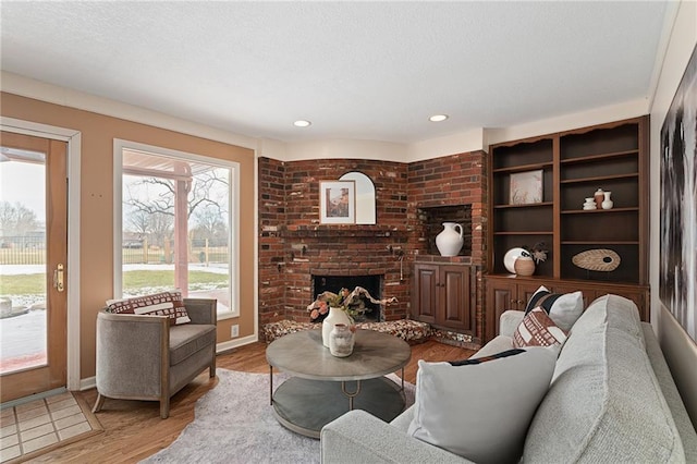 living area featuring a textured ceiling, wood finished floors, recessed lighting, a fireplace, and baseboards