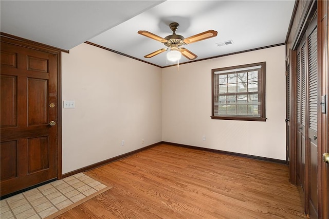 entryway featuring visible vents, baseboards, light wood-style floors, and ornamental molding