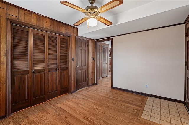 unfurnished bedroom with ceiling fan, a closet, baseboards, and light wood-style flooring