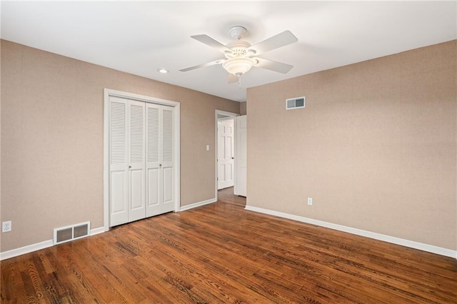 unfurnished bedroom featuring a closet, visible vents, baseboards, and wood finished floors