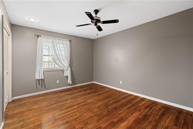 unfurnished room with baseboards, dark wood-type flooring, and ceiling fan