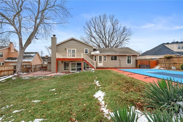 back of property featuring a fenced backyard, a lawn, a chimney, and a patio