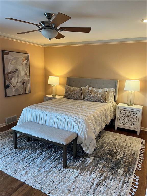 bedroom featuring visible vents, crown molding, ceiling fan, and wood finished floors