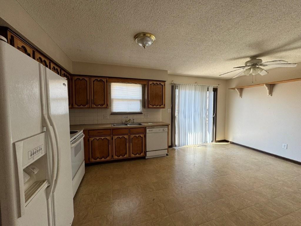 kitchen featuring white appliances, a ceiling fan, light floors, a sink, and decorative backsplash