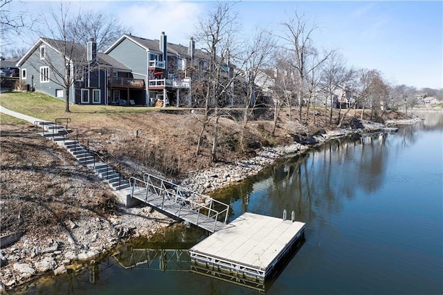 view of dock with a deck with water view, a lawn, and stairs