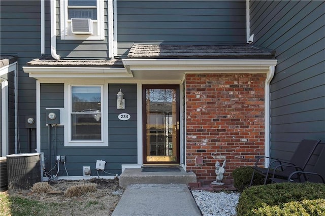 property entrance with brick siding and cooling unit