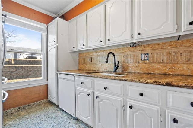 kitchen with ornamental molding, dark stone countertops, white dishwasher, white cabinets, and a sink