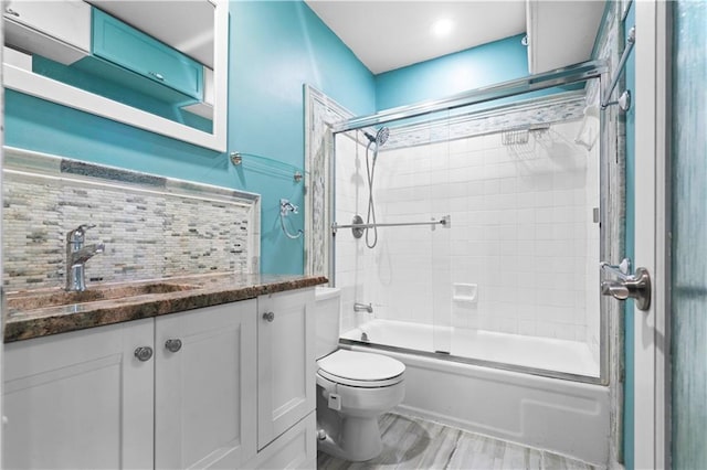 full bath with backsplash, toilet, vanity, and shower / bath combination with glass door