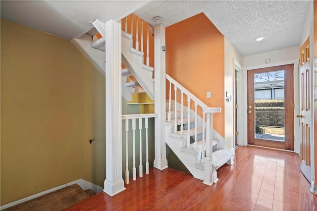 foyer entrance with stairs, wood finished floors, baseboards, and a textured ceiling