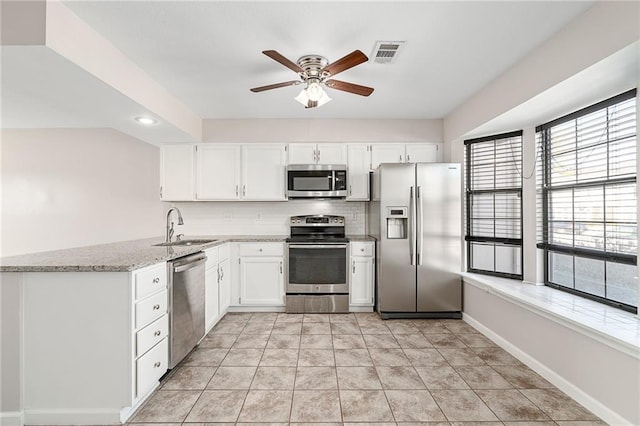 kitchen featuring visible vents, ceiling fan, light stone countertops, appliances with stainless steel finishes, and a sink