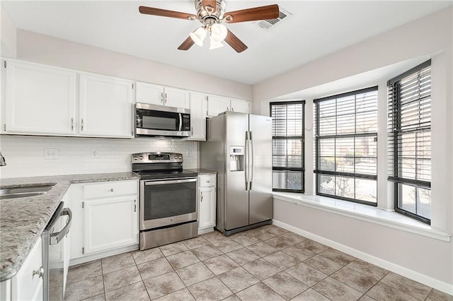 kitchen featuring visible vents, a ceiling fan, light stone counters, stainless steel appliances, and decorative backsplash