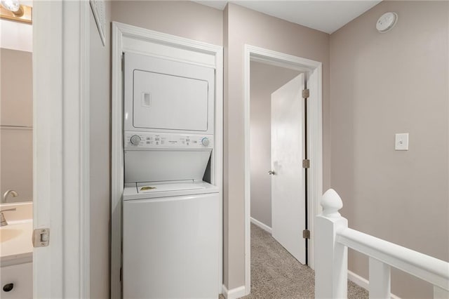 washroom featuring baseboards, carpet, laundry area, and stacked washer / dryer