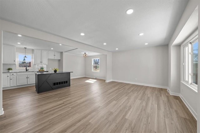 unfurnished living room featuring recessed lighting, a healthy amount of sunlight, baseboards, and light wood finished floors