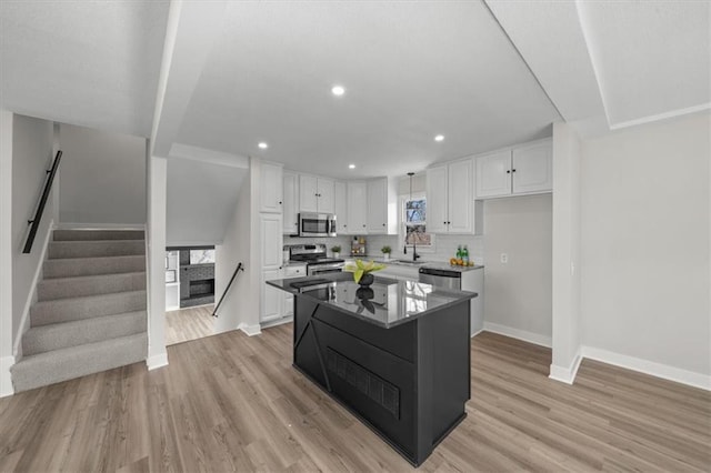 kitchen featuring light wood-type flooring, tasteful backsplash, appliances with stainless steel finishes, and white cabinetry