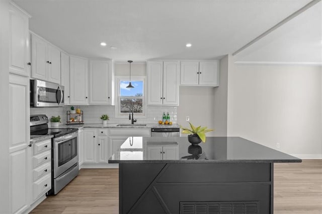 kitchen with a sink, stainless steel appliances, light wood-style floors, and white cabinetry