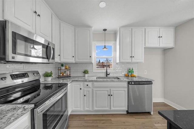 kitchen featuring light stone counters, appliances with stainless steel finishes, white cabinetry, and a sink