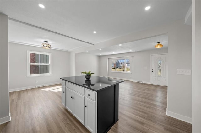 kitchen featuring dark countertops, open floor plan, white cabinetry, and wood finished floors