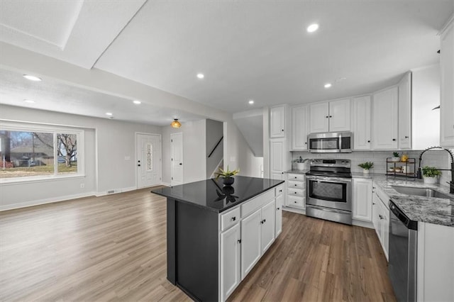 kitchen with light wood-style flooring, a sink, white cabinets, appliances with stainless steel finishes, and tasteful backsplash