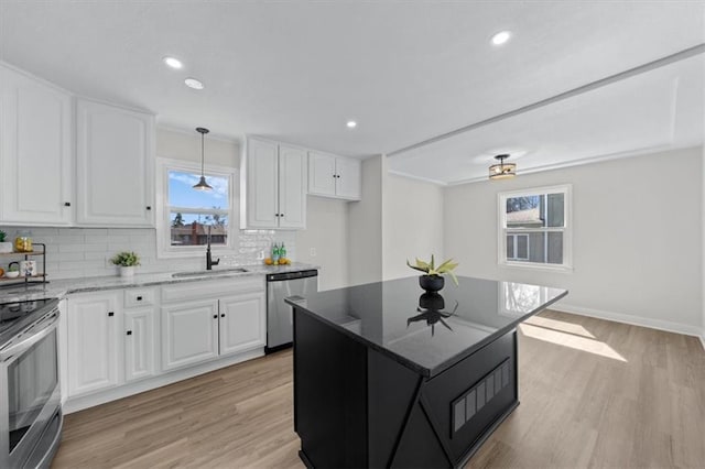 kitchen featuring a sink, stainless steel appliances, plenty of natural light, and dark stone counters