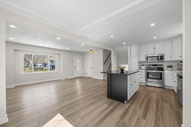 kitchen with baseboards, open floor plan, light wood-type flooring, appliances with stainless steel finishes, and white cabinets