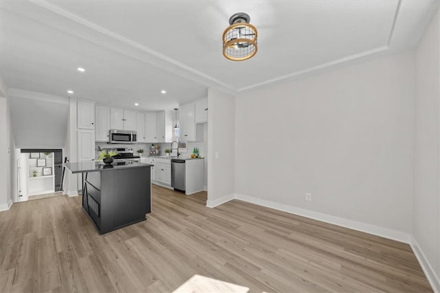 kitchen with light wood finished floors, baseboards, white cabinets, stainless steel appliances, and a sink