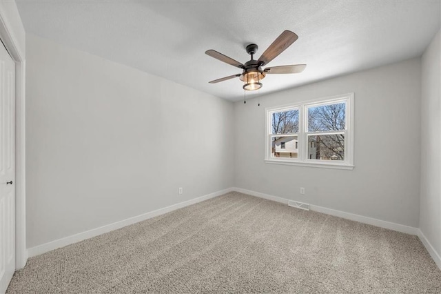 carpeted empty room with a ceiling fan, baseboards, and visible vents