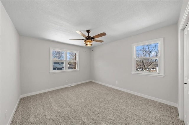 spare room with visible vents, a ceiling fan, a textured ceiling, carpet, and baseboards