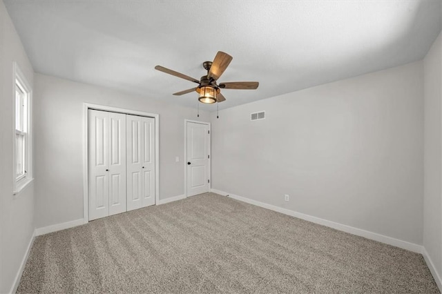 unfurnished bedroom featuring a ceiling fan, carpet, visible vents, baseboards, and a closet