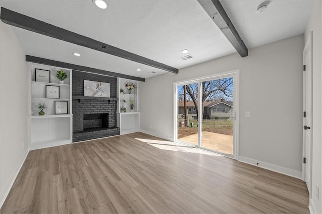 unfurnished living room featuring a fireplace, beam ceiling, wood finished floors, and baseboards