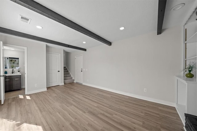 unfurnished living room with visible vents, beamed ceiling, light wood-style flooring, and stairs