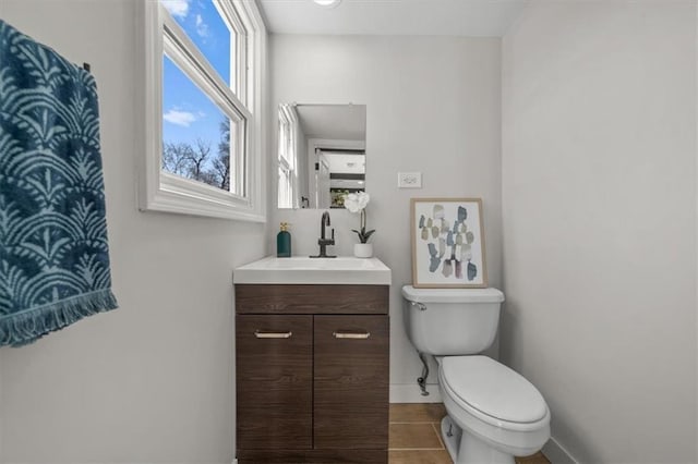 half bathroom featuring vanity, toilet, and baseboards