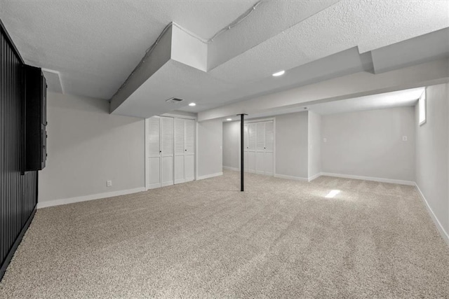 finished basement featuring visible vents, a textured ceiling, recessed lighting, carpet flooring, and baseboards