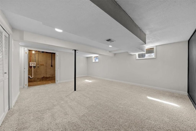 below grade area with baseboards, visible vents, and carpet floors