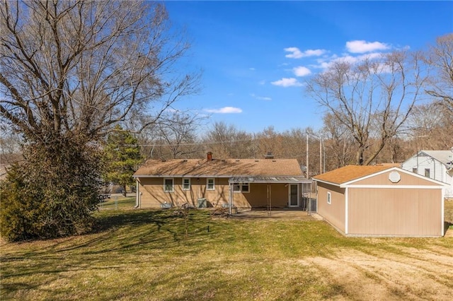 rear view of house featuring an outbuilding, a yard, and a patio area