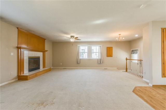 unfurnished living room featuring a tiled fireplace, light colored carpet, and baseboards