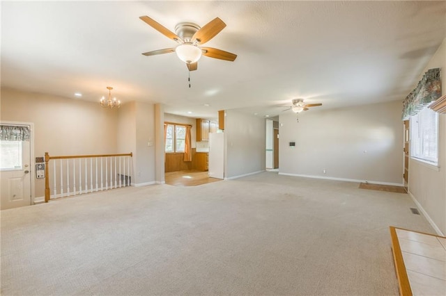 spare room with baseboards, light colored carpet, and ceiling fan with notable chandelier