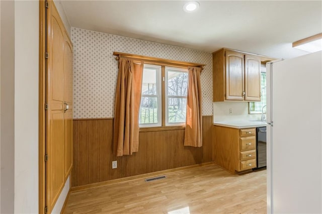 kitchen featuring a wainscoted wall, light wood-style floors, visible vents, and wallpapered walls