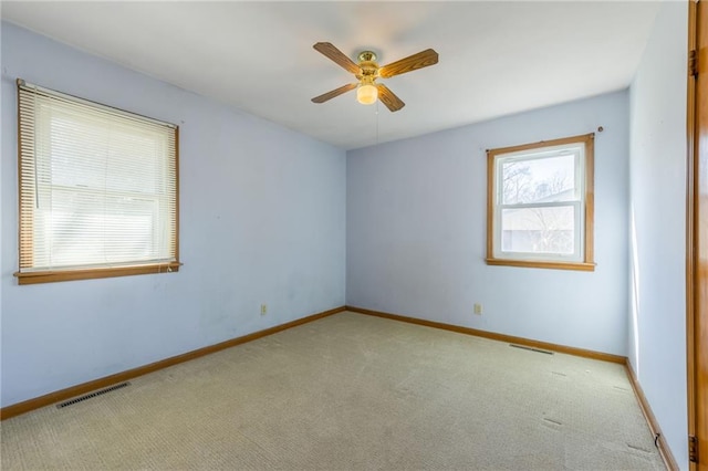 carpeted empty room with baseboards, visible vents, and ceiling fan